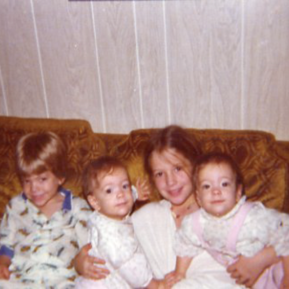Sibling photo as kids sitting on a gold sofa.