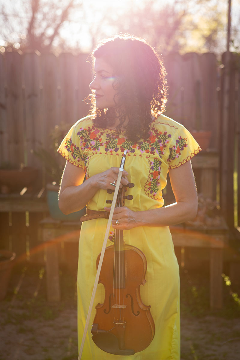 Carrie photographed in a yellow dress holding a violin