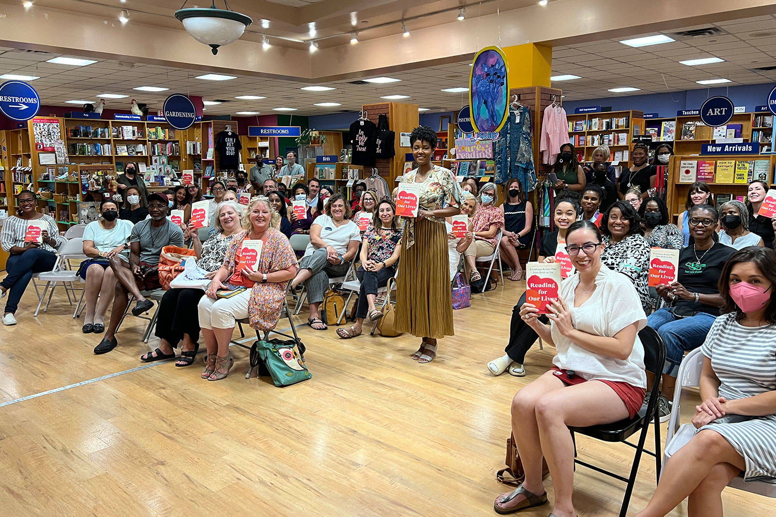 Maya smiles in front of an audience while holding her book at BookPeople in Austin, Texas.