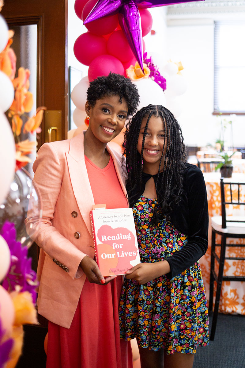 Maya and her daughter Zora hold Maya’s book “Reading for Our Lives”.