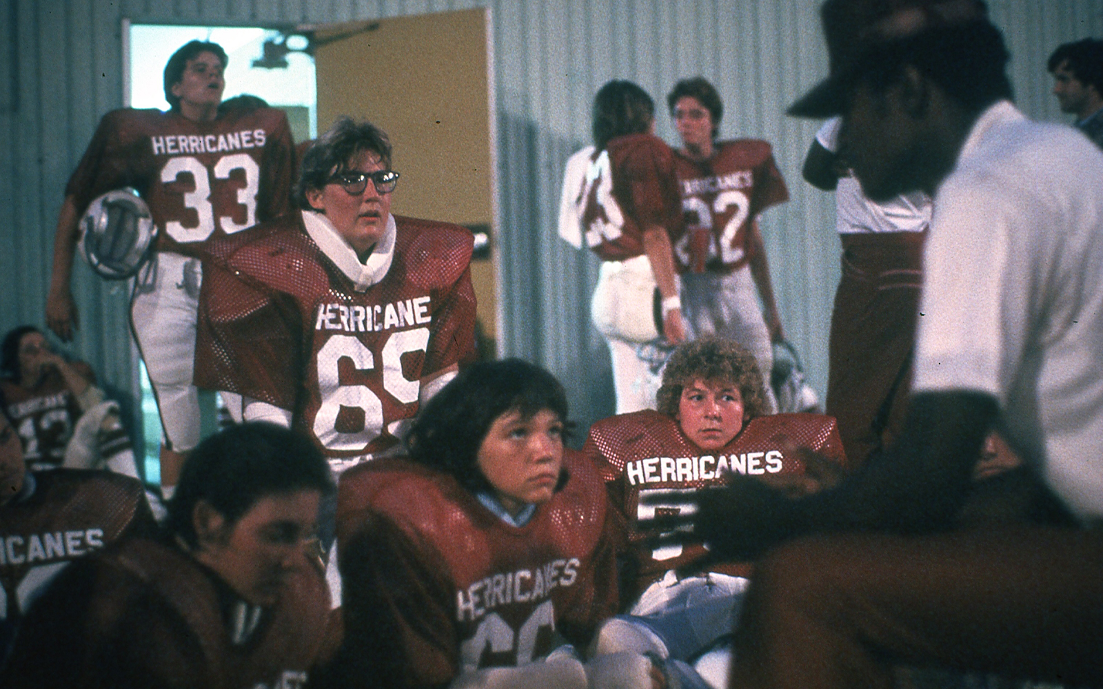 The Houston Herricanes offensive line players wearing their uniforms in the locker room listening to their coach Tommy Tillman at halftime.
